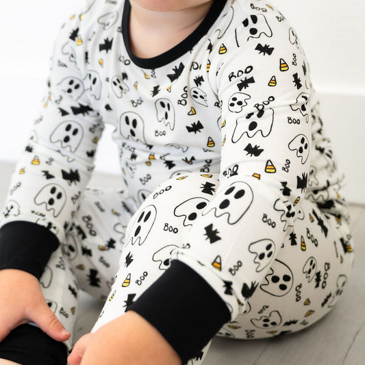 Baby wearing a Halloween-themed onesie with ghosts, bats, and candy corn on a white background.