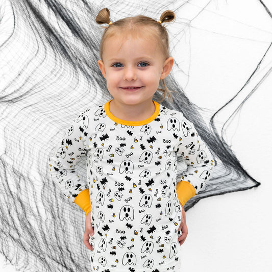 Child wearing a Halloween-themed onesie with spider webs in the background