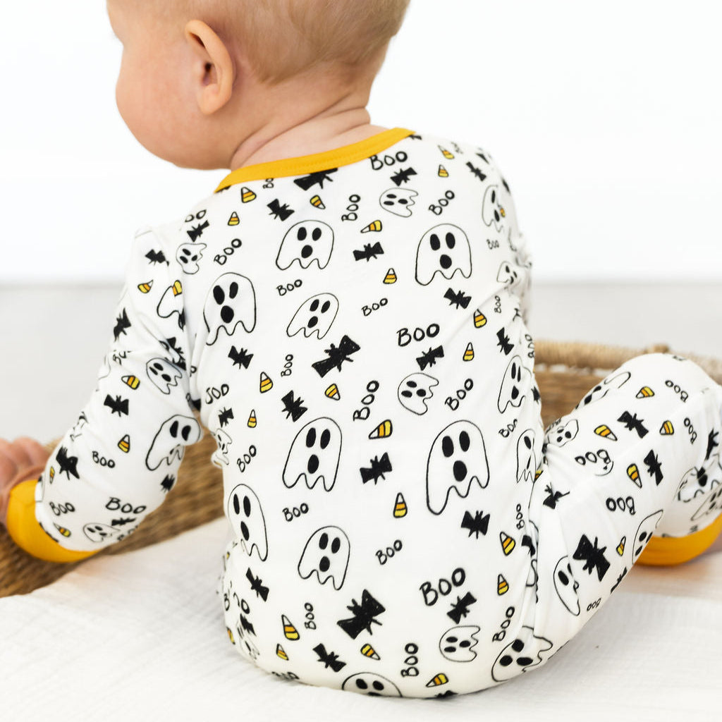 Baby wearing a Halloween-themed onesie with ghosts, bats, and candy corn on a white background.